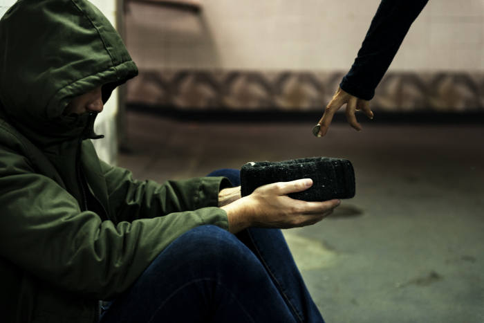 A beggar holding up his wallet to receive money.